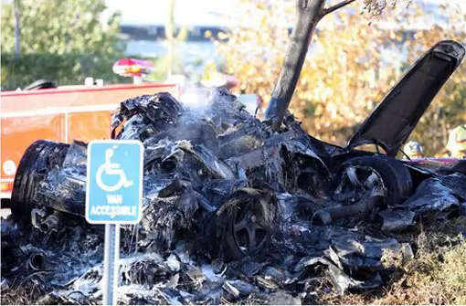 Carefully lined up shot of a "Van Accessible" sign in front of the burned out wreck of what was supposedly Roger Rodas and Paul Walker's Porsche Carrera GT.